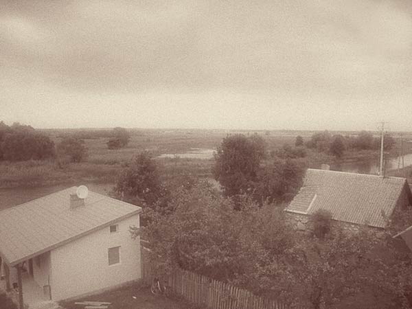 Tykocin 2011, kilka domów i dalej za Narwią rozległe łąki.